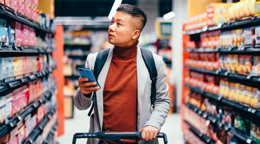 Un bel homme asiatique recherche des produits d'épicerie dans la liste sur son téléphone.