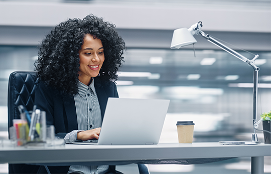 A black woman is working on her computer at a desk