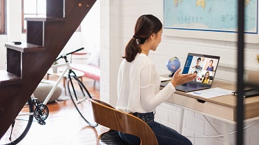 Woman seated at a table participating in a video conference