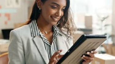A businesswoman smiling while scrolling on a tablet.
