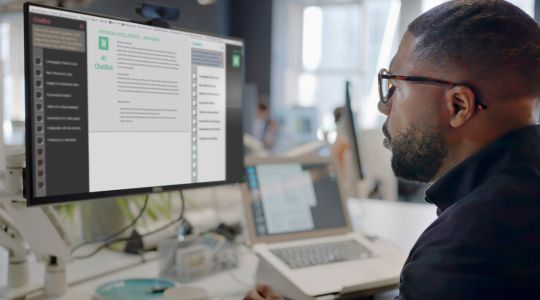 A man looking at a computer screen displaying an artificial intelligence chatbot. 