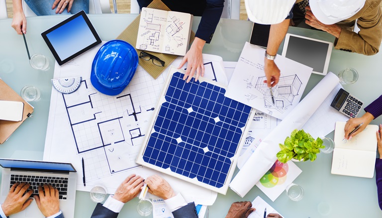 Cleantech company leaders look over blueprint drawings in office.