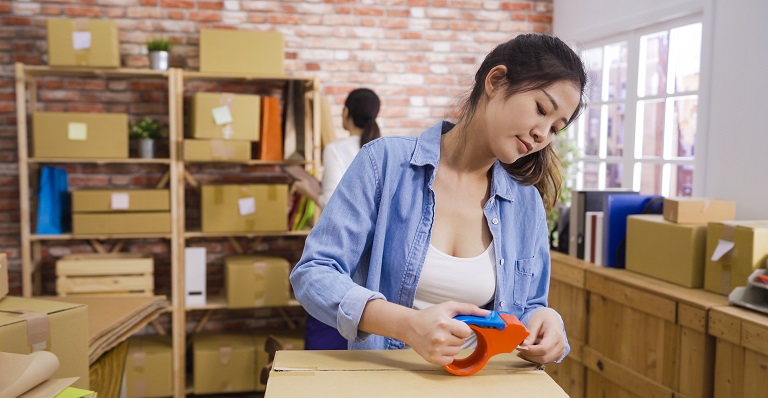 Two female Asian entrepreneurs pack boxes intended for customers