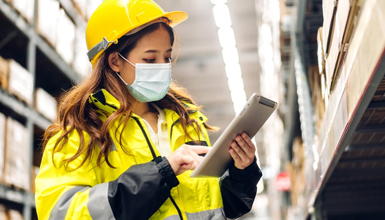 Asian-Canadian engineer checks details on warehouse tablet