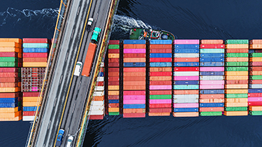 A container ship passes beneath a suspension bridge as it departs for Europe