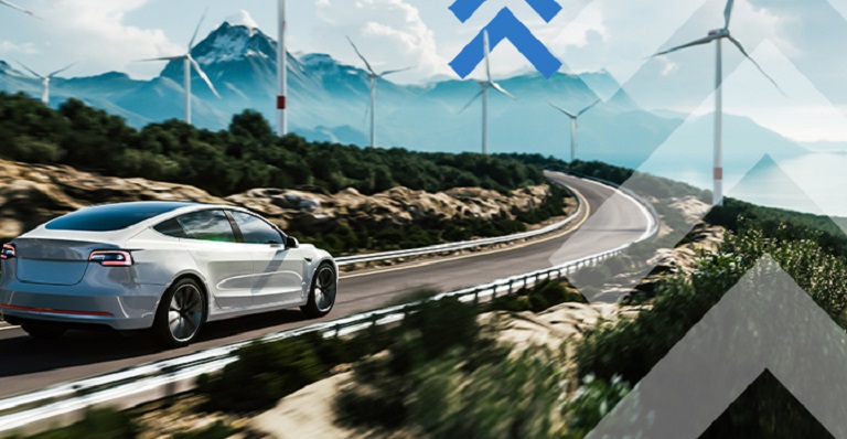 An electric car on a highway with wind turbines and mountains in the distance.