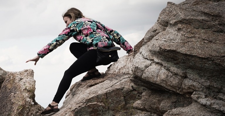 Female hiker attempts a risky manoeuvre while climbing between two rocks.
