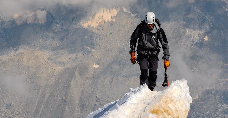 Male climber tackles dangerous snowy mountaintop