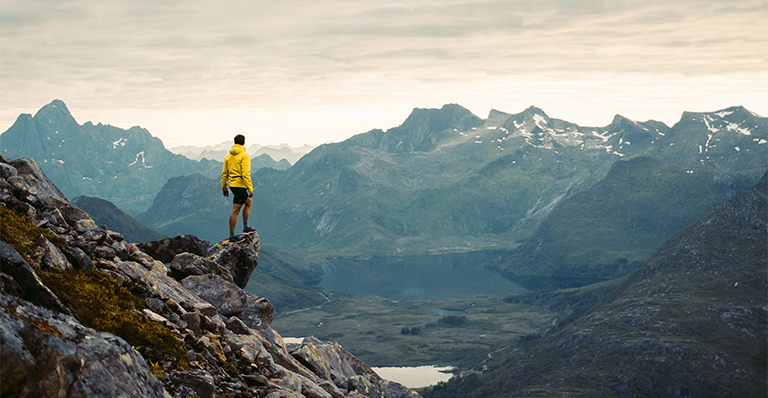 Hiker stands on edge of mountain