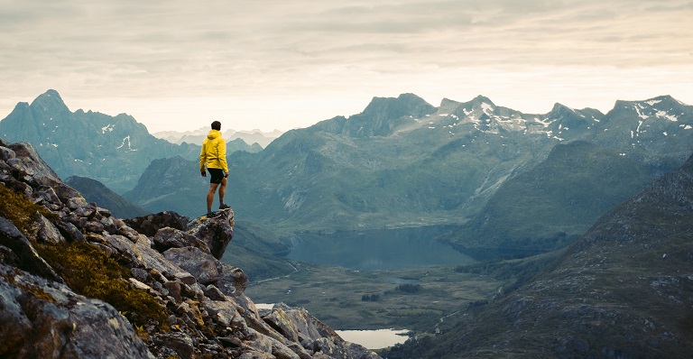 Male hiker stands on precarious mountain ledge