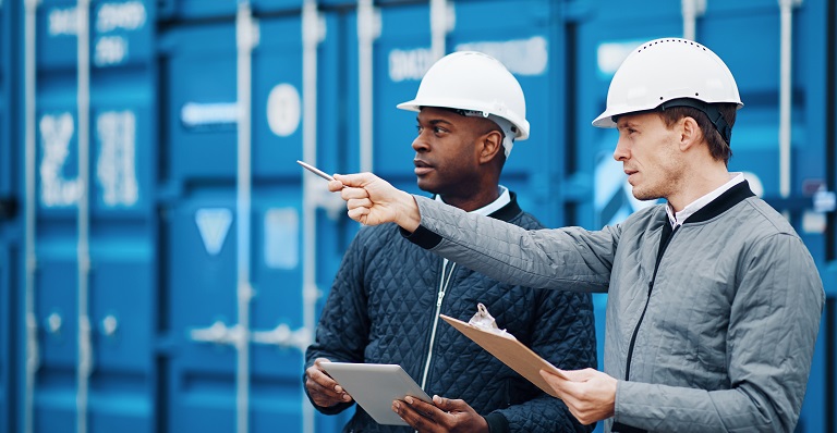 Two exporters discuss shipment in front of container