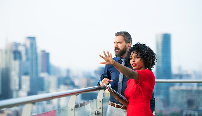 Two individuals talking outside and looking at the horizon. 