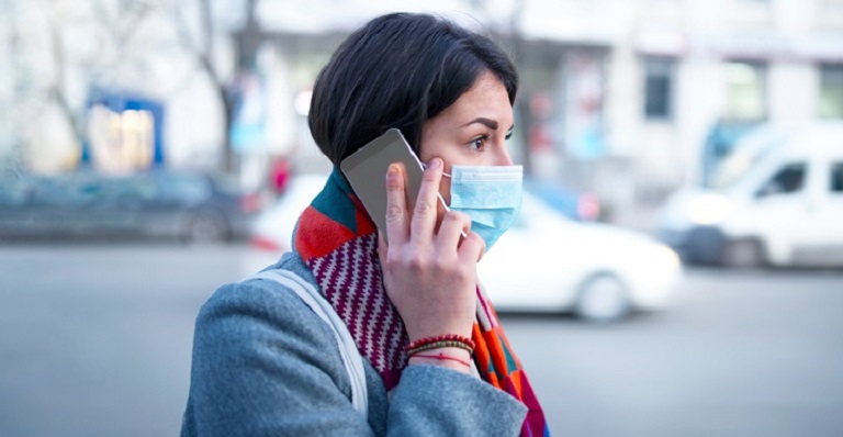 Photo of a professional woman wearing a facemask talking on the phone