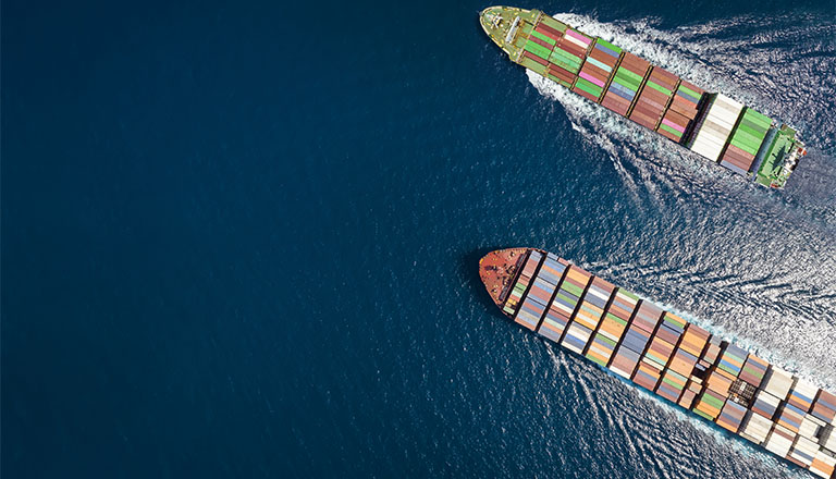 High aerial top down view of two container cargo ships traveling over open ocean