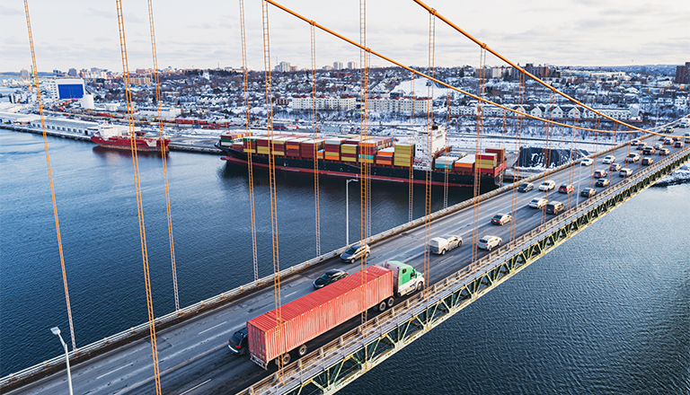 Bridge with truck and cargo ship in the back 