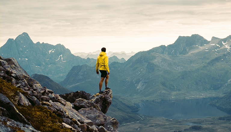 A man hiking in a rugged natural environment standing over a cliff.