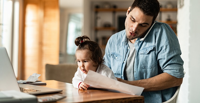 Un homme d’affaires travaille à la maison tout en surveillant sa petite fille.