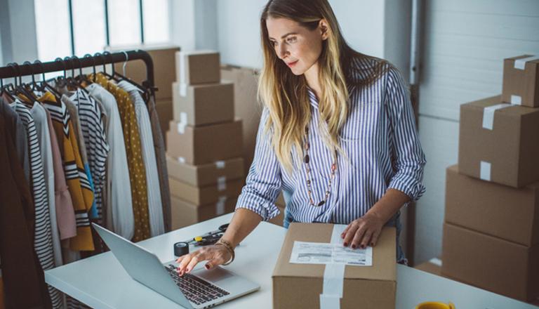 A small business owner is packing her product in boxes, preparing it for delivery.