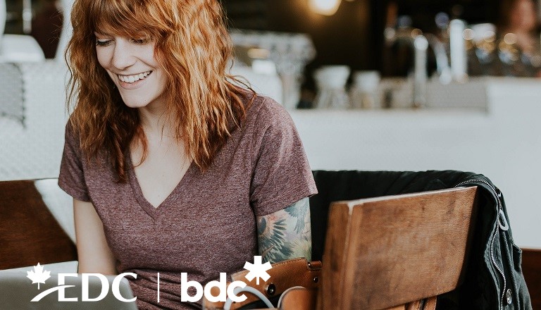 Installée dans un café, devant son ordinateur portable, une jeune entrepreneure réalise des ventes en ligne.